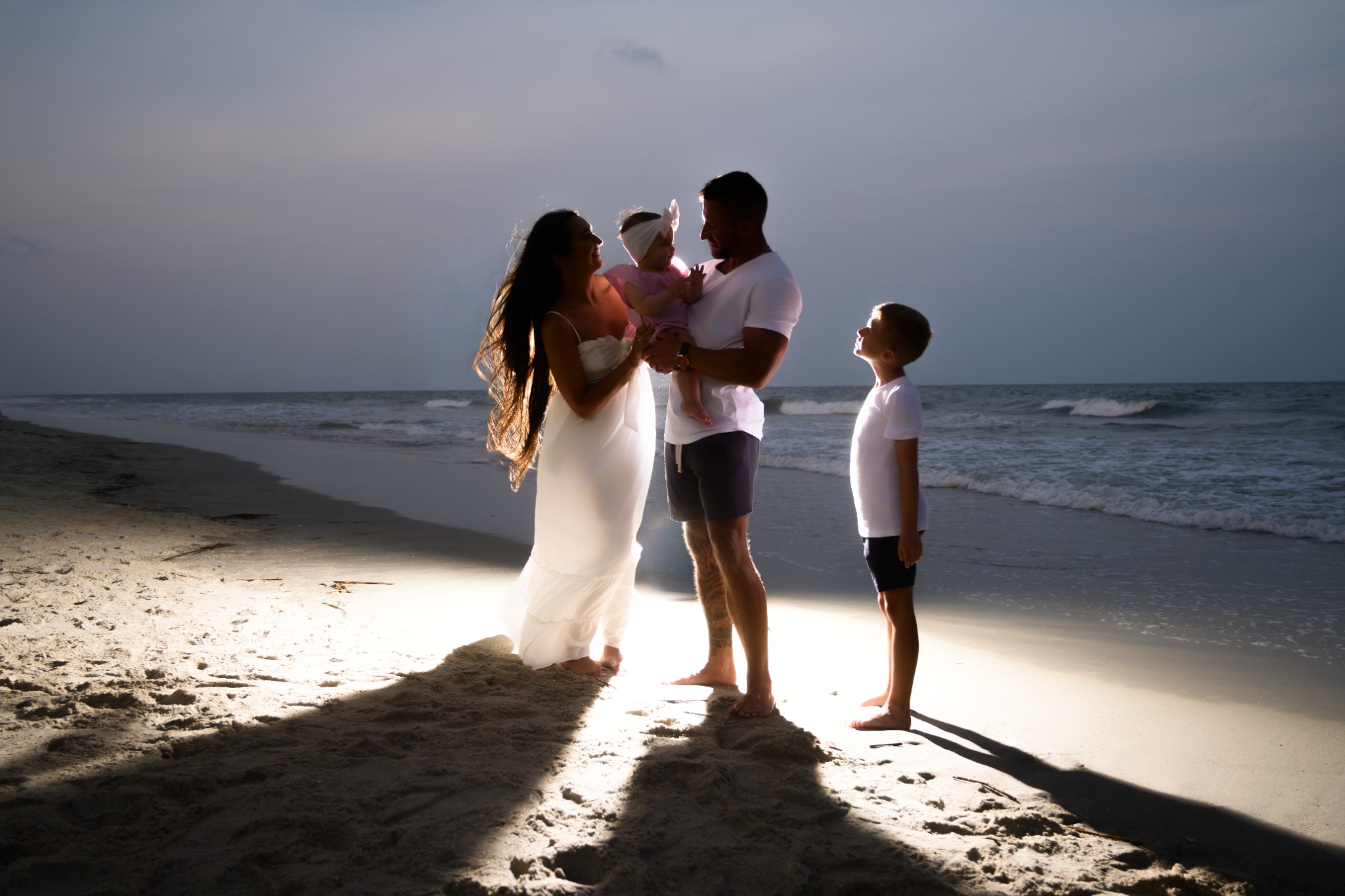 Family with two young children photographed together on the coast