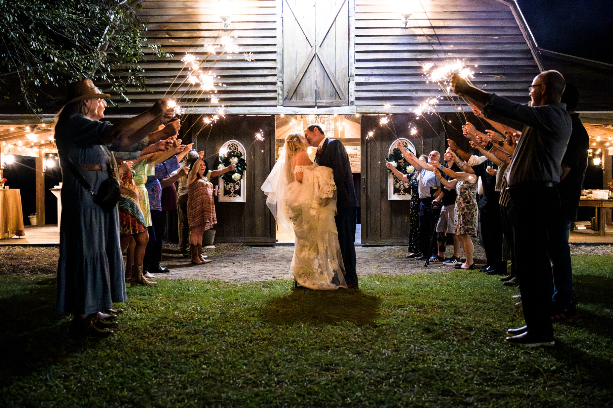 Newlyweds kissing during a sparkler exit outside the barn at Wildhorse at Parker Farms